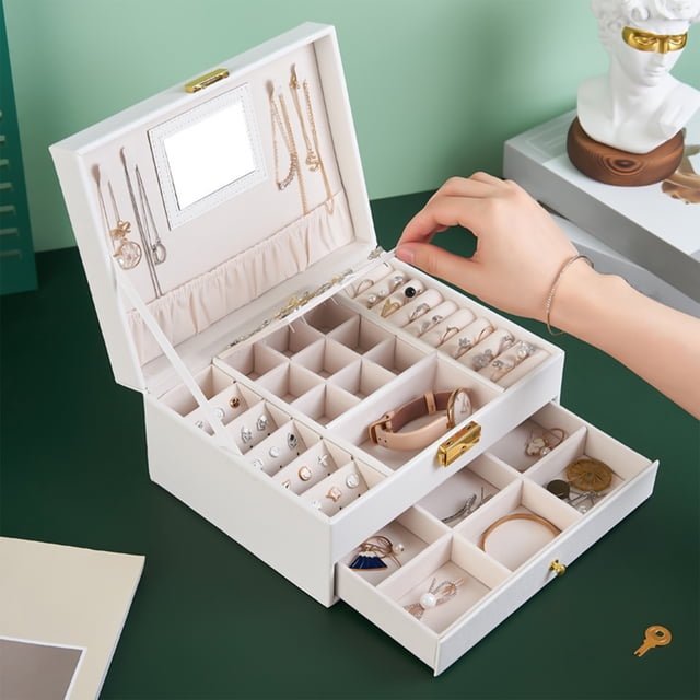 Vaidha Jewelry Box With Lock And Mirror Jewelry Organizer Storage Case With 2-Layers Display for Earrings, Bracelets, Rings, and Watches. The white leather box features a double-layer design with multiple compartments, necklace hooks, and a built-in mirror. A hand is seen accessing the organized compartments, which hold various jewelry pieces. Includes a secure lock with a key, making it ideal for safe storage and gifting occasions like birthdays or anniversaries.