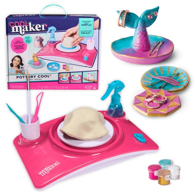 Cool Maker Ensemble d'Artisanat de Tour de Poterie en Argile à Séchage à l'Air pour Enfants de 8 Ans et Plus, Comprenant une Tour de Poterie Rose et Blanche avec un Disque en Argile sur le Plateau Tournant, des Outils de Sculpture dans un Support, une Bouteille Vaporisateur Bleue et Cinq pots de Peinture Métalliques, aux Côté de Trois Plats de Poterie Peints Utilisés comme Porte-Bijoux avec Anneaux et Pinces à Cheveux.