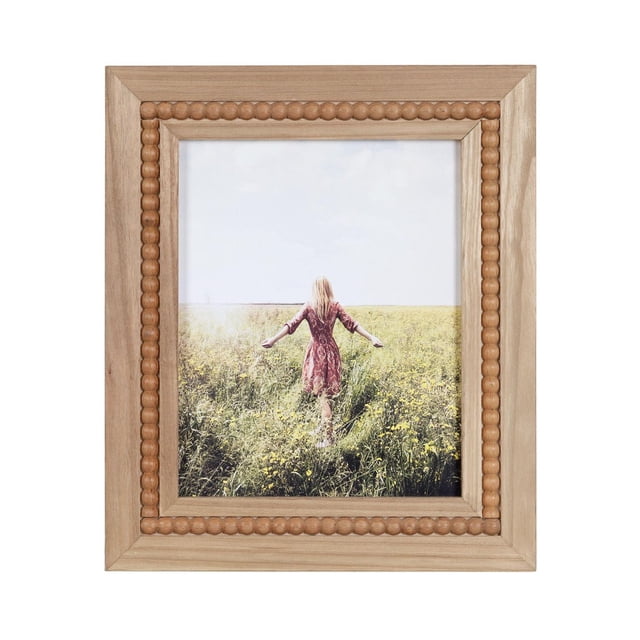 hometrends Sorel Picture Frame with natural wood finish and inset beaded detailing, fits 8x10 photos, shown displaying a photo of a woman in a red dress walking through a yellow flower field, includes easel for tabletop or wall hangers for versatile display, suitable for home décor and gifting.
