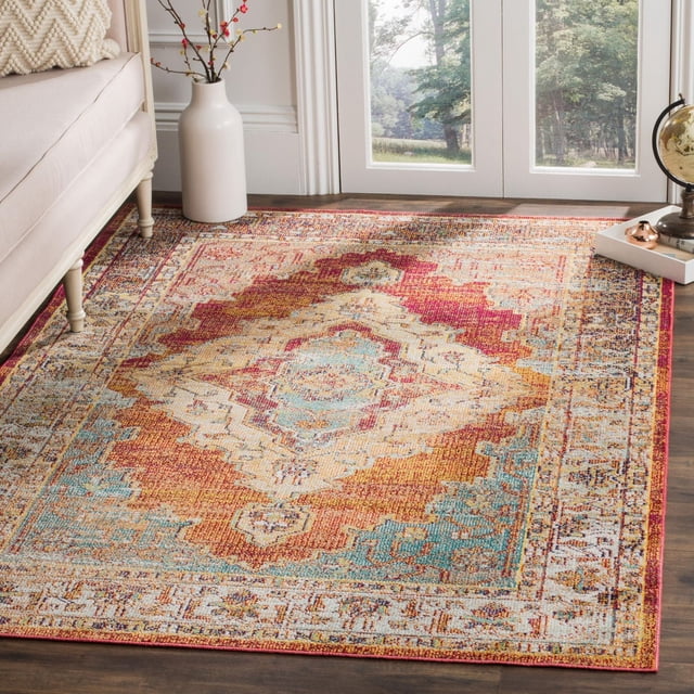 Safavieh Crystal Miranda Traditional Area Rug with close cut synthetic yarn pile featuring an intricate floral medallion pattern in red, orange, blue, and beige, placed on hardwood floor near a beige sofa and white vase by glass doors, ideal for transitional living or dining rooms.