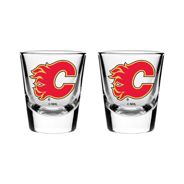 The Sports Vault 2PK Shot Glass Set Calgary Flames with two clear 2oz glass shot glasses featuring the Calgary Flames red and yellow flaming C logo, made of 100% glass and dishwasher safe, suitable for barware or gifting to sports fans.