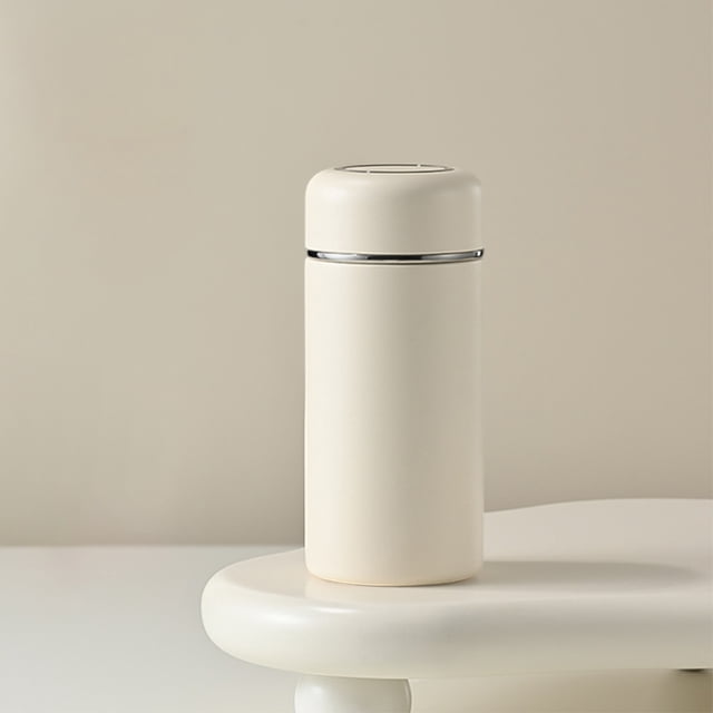 EGNMCR Tasse Isotherme de Poche mini Compacte en Acier Inoxydable 316 Blanche, Présentant un design Cylindrique Épuré avec un accent Argenté Poli Près du Couvercle. Cette Tasse de Voyage Est Conçue pour la Portabilité et la Rétention de la Température, Idéale pour les Boissons Chaudes Ou Froides. Positionnée sur une surface Blanche Minimaliste.