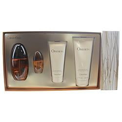 Calvin Klein Gift Set Obsession By Calvin Klein featuring a 3.4 oz eau de parfum spray, 6.7 oz body lotion, 3.4 oz shower gel, and 0.5 oz mini eau de parfum spray. The set is displayed in a sleek packaging with a gold-toned interior and includes bottles and tubes with the Obsession branding. This oriental spicy fragrance, introduced in 1985, blends notes of basil, peach, vanilla, lemon, bergamot, jasmine, and amber, ideal for daytime use.