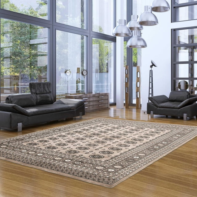 Tekke Oriental Area Rug for Living Room, Dining Room, Bedroom shown in a modern living room with large windows. The grey rug features traditional symmetrical oval and diamond motifs on a beige background, placed on a hardwood floor between two black leather sofas. Its soft pile and classic design add refined elegance, also suitable as an accent rug in various home spaces.
