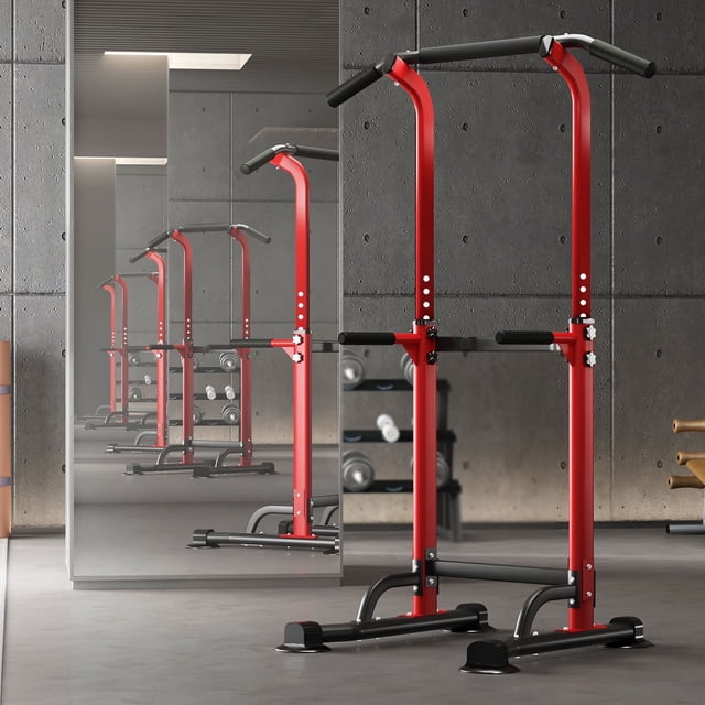 SogesPower Adjustable 82.7"H Pull up Bar Power Tower Multifunctional Fitness Station for Home. A red and black heavy-duty metal frame with adjustable height from 65" to 82.7". Features non-slip grips, a splayed anti-eversion base, and vinyl padding for stability and comfort. Suitable for pull-ups, dips, push-ups, and more, supporting up to 330lbs. Displayed in a modern gym setting with a mirrored wall and fitness equipment in the background.