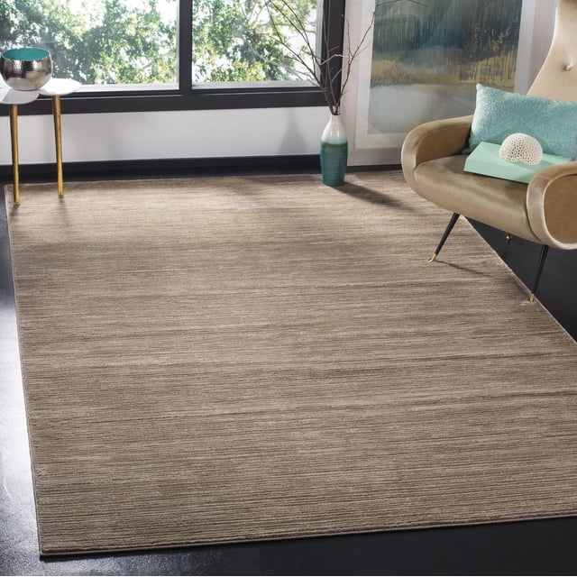 Safavieh Vision Tapis Uni Surteint Adrasteia pour Salon Contemporain, Présentant un Grand Tapis d'Accent Rectangulaire beige à texture Linéaire Subtile sur un Plancher Sombre, Complété par un Fauteuil beige avec Coussin Sarcelle et Corail Décoratif, un Grand vase avec des branches, et une Petite table d'Appoint Ronde avec Bol Métallique Près d'Une Grande Fenêtre.