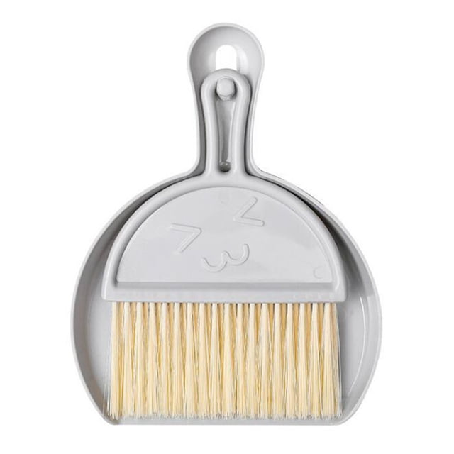 Mini Broom and Dustpan Set in grey, featuring a dustpan with a cute embossed face design and a matching brush with light bristles. Compact cleaning tool set ideal for desks, kitchen counters, and small spaces. Includes hanging holes for easy storage. Perfect for household cleaning tasks.