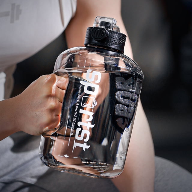 Gourde de Grande Capacité par LEUTSIN, une Bouteille d'Eau Transparente avec Poignée Noire et Couvercle à Paille Étanche, Conçue pour les sports et les Activités de Plein Air. la Bouteille a une Capacité de 1700 ml et Présente une Construction en Plastique durable avec une Corde de Transport et un Étui en Cuir. Montré en Utilisation, Tenu par une Personne dans un Cadre de gym.