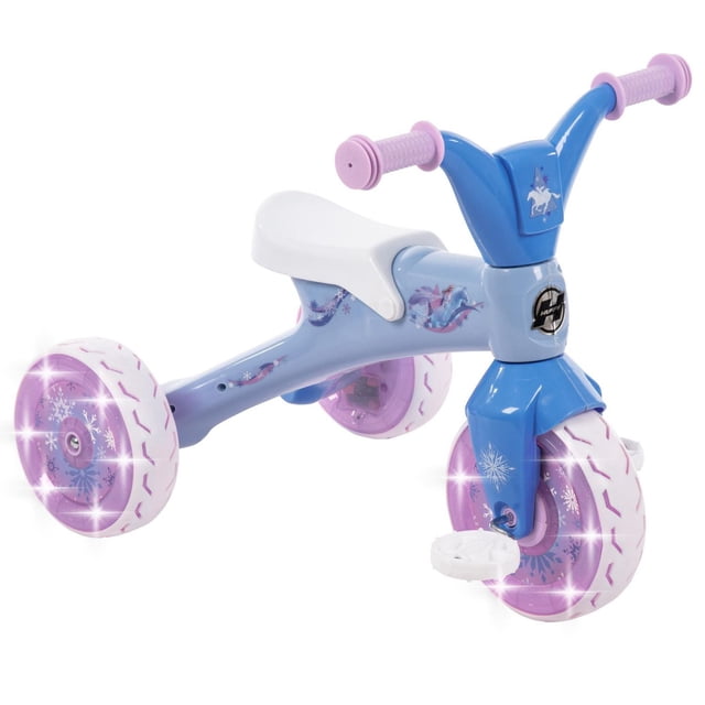 Disney Frozen Electro Light Trike for Kids by Huffy with a blue frame, white seat, and pink grips. It features LED lights inside purple wheels decorated with snowflakes and Frozen-themed graphics, including a unicorn on the handlebar. The trike includes under-seat storage and white pedals, designed for toddlers 18 months to 3 years and max weight 44 lbs.