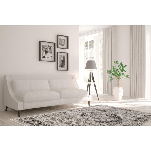 Zunthus Tapis Tissé beige et Brun avec un Motif Oriental Délavé en Gris Anthracite Poussiéreux sur Blanc Cassé, Posé sur un Plancher de Bois Clair dans un Salon Lumineux. le Tapis en Polypropylène à Profil Bas Se Tient devant un sofa beige avec des Pattes en Bois, Près d'Une Lampe sur Pied Trépied avec un Abat-Jour Gris et un Cache-Pot Blanc Tenant une Plante Feuillue Verte. Trois photos Florales Noir et Blanc Pendent au-Dessus du sofa, Complétant le Décor Rustique et Contemporain.