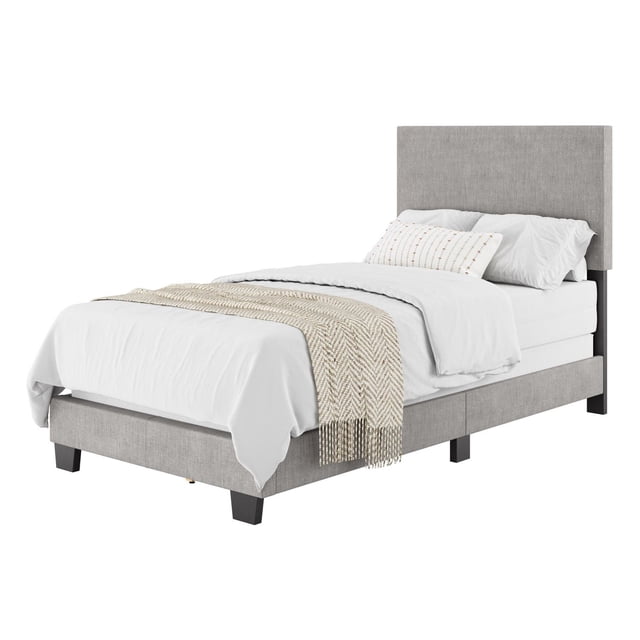 CorLiving Celeste Modern Upholstered Adult Twin Bed Frame with Headboard in light grey fabric, featuring a padded headboard and dark wooden legs, styled with white bedding and a beige textured throw, suitable for creating a calm and cozy bedroom.