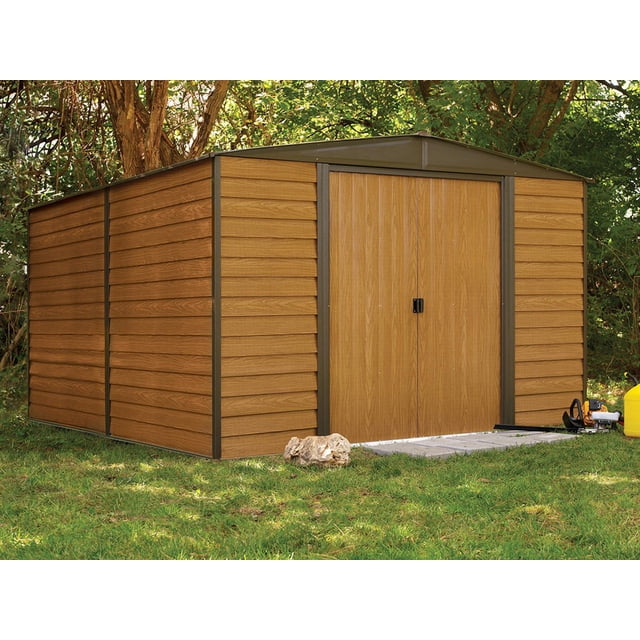 Woodridge Remise de Rangement en Acier 10 x 12 Pi Café/grain de Bois Vue avant Trois-Quarts Montrant Toit à Pignon et Doubles Portes. Remise Rectangulaire en Acier à Murs Hauts avec Panneaux Enduits de Vinyle Grain de Bois Café, Cadre Traité au Zinc Galvanisé Électrolytiquement et Fini Résistant aux UV; Convient aux Tondeuses à Gazon, aux Meubles de patio et au Rangement Saisonnier, et Est Souvent Utilisée comme Atelier de Cour Arrière Ou Rangement Sécuritaire pour Vélos.