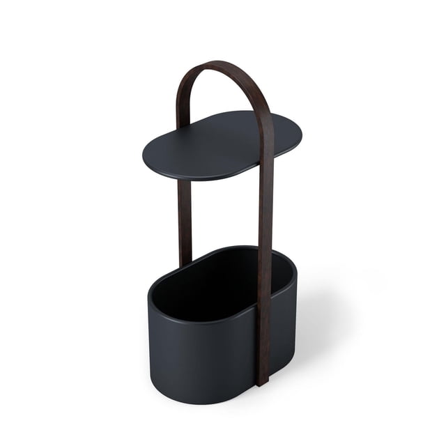 Umbra Bellwood Storage Table in black and walnut, featuring a modern oval black metal tabletop supported by a walnut wood arch frame. The base is a black oval storage container for organizing cables, books, or blankets, with an integrated handle for easy transport, suitable for cable management and versatile storage.