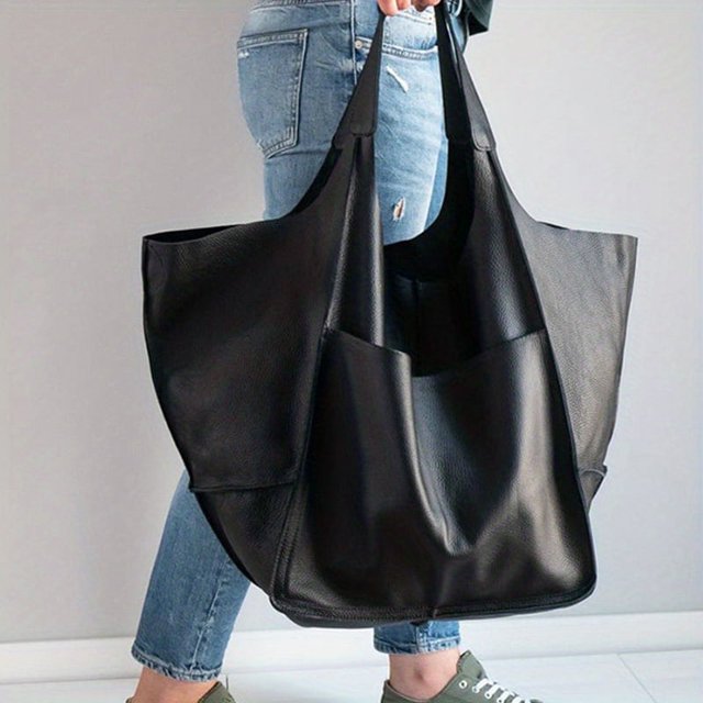 Rretro Big Tote Bag, a solid color large-capacity zipper shoulder tote bag made of synthetic material. The bag features a minimalist design with no pattern, fixed shoulder straps, and a magnetic closure. Shown in black, it is being carried by a person wearing casual jeans and sneakers.