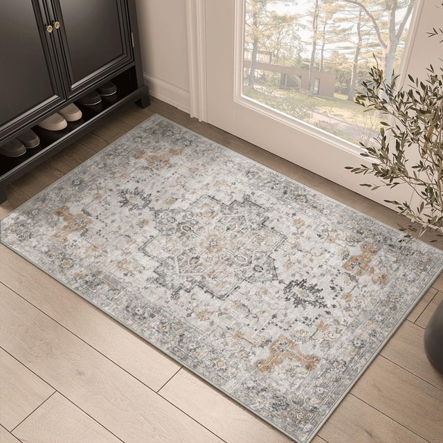 KUETH 2'x3' area rug for living room, featuring a vintage-inspired chenille print in muted tones of gray and beige. This ultra-thin, low-pile rug is machine washable and designed with a non-slip rubber backing for stability on hardwood or tile floors. Shown in a bright indoor setting near a doorway, the rug complements modern and traditional decor styles.