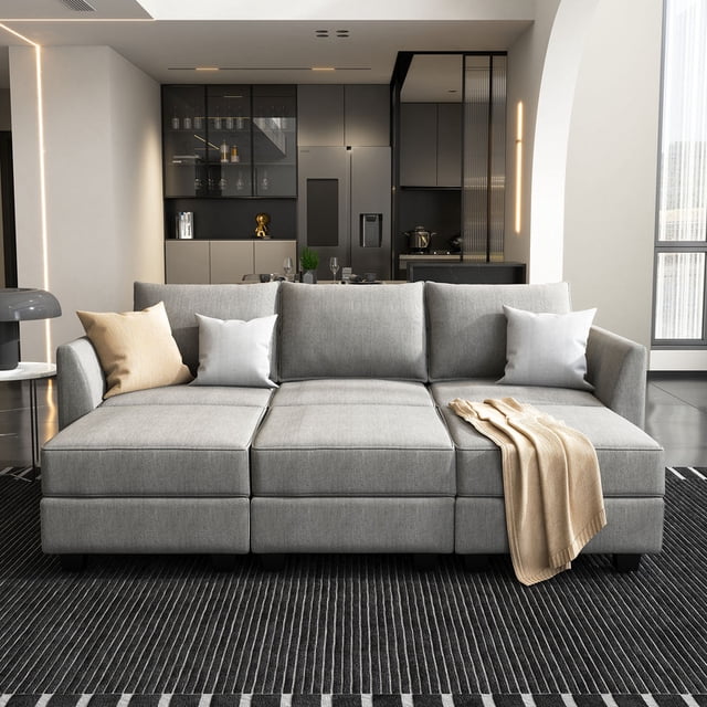 HONBAY Modern Modular Polyester Couches and Convertible Sofas Sectional with Storage for Living Room and Bedroom, Grey. The sectional sofa features a modular design with breathable grey polyester fabric and hidden storage under each seat. It is shown in a modern living room setting with a striped black rug and neutral-toned throw pillows. The sofa can be rearranged into various configurations, including an L-shape, U-shape, or sleeper sofa, accommodating up to two people. Dimensions: 87 W x 55.90 D x 33.86 H inches. Ideal for compact spaces and easy to assemble.