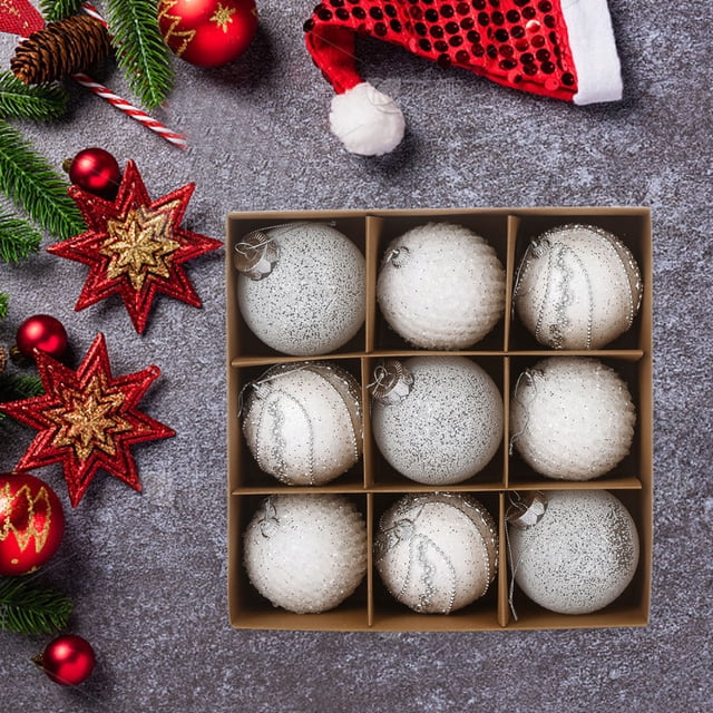 Meitianfacai 8cm Christmas Balls 9pcs set featuring white plastic ornaments with sequins and lace designs. Perfect for Christmas tree decorations or holiday decor, the balls are displayed in a grid-style box against a festive background with red and gold holiday decorations, including stars, pinecones, and a Santa hat.