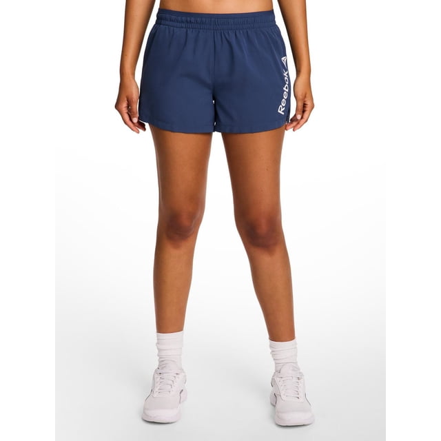 Reebok Women's Staple Running Short with Mesh Lining in navy blue, made from lightweight polyester with quick-drying fabric, elastic waistband with drawcord, side slits, and vertical Reebok logo on the left leg, ideal for running or training and often used for casual activewear.