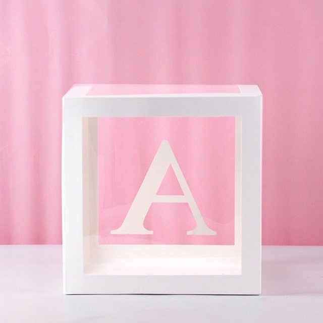 Baby Girl Birthday Party Decorations Letters Box Kit featuring a white transparent cube with the letter 'A' printed on the front. Ideal for baby showers, birthday parties, and photo shoot props, the eco-friendly box measures 30x30cm and is made of durable paper and plastic. Designed to hold balloons, it creates a festive atmosphere. Displayed against a pink backdrop.