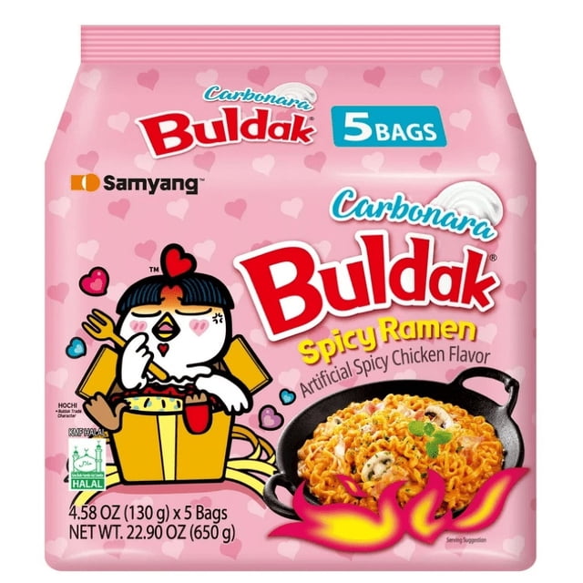 Samyang – Ramen Carbonara au Poulet Épicé Buldak 130 g x Lot de 5 avec Emballage à Motif de Cœurs Roses Mettant en Vedette une Mascotte de Poulet Dessin Animé Tenant une Fourchette, Certifié Halal, Montrant une Casserole en Fonte de Nouilles Instantanées Épaisses et Moelleuses dans une sauce Carbonara Épicée avec des Champignons et une Garniture.