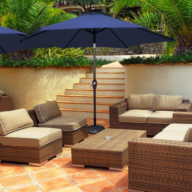 Costway Parasol de Marché pour Patio de 10 Pieds à DEL Solaires, Inclinaison Réglable, Manivelle, Bleu Marine, Exposé dans un Patio Extérieur Moderne. le Parasol Présente une Auvent en polyester Bleu Marine Soutenu par un Poteau en Fer Enduit de Poudre et six Nervures Robustes. Il Comprend 18 Lumières DEL à Énergie Solaire pour l'Éclairage Nocturne et un Mécanisme à Manivelle pour une Ouverture et une Fermeture Faciles. l'Inclinaison à Bouton-Poussoir Permet d'Ajuster l'Angle de l'Auvent pour une Ombrage optimal Toute la Journée. une Éventre Améliore la Résistance au vent et Favorise la