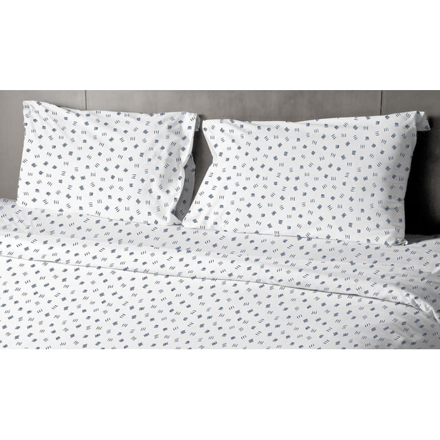 Johnson Home 200 TC Bed Sheet Set - Printed Cotton Sheets with a white background and scattered navy blue abstract shapes, including short lines and rectangles, shown on a bed with two matching pillowcases and a grey headboard, crafted from breathable cotton for year-round comfort.