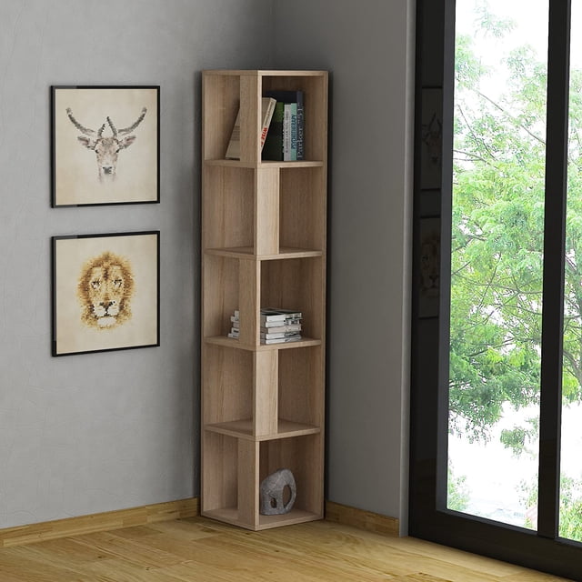 JV Home Piano Collection 64 Inch 5-Tier Corner Bookcase in oak finish, featuring a modern design with sloping angles and five spacious shelves for books, decor, and storage. Made from durable manufactured wood with a melamine coating, it is shown placed in a corner of a room with framed wall art and a large window overlooking greenery.