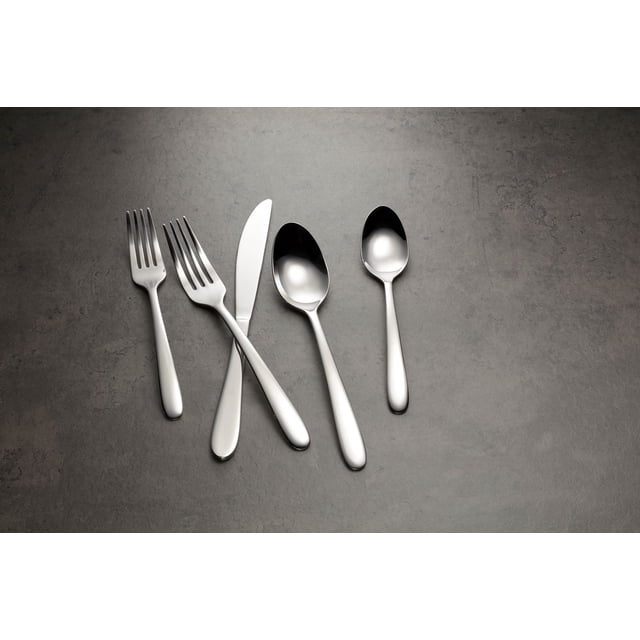 Cambridge Haledon Mirror 77 Piece Flatware Set showing a close-up of five polished 18/0 stainless steel utensils with mirror finish including salad fork, dinner fork, dinner knife, dinner spoon, and teaspoon on a grey textured surface, suitable for everyday and formal dining.