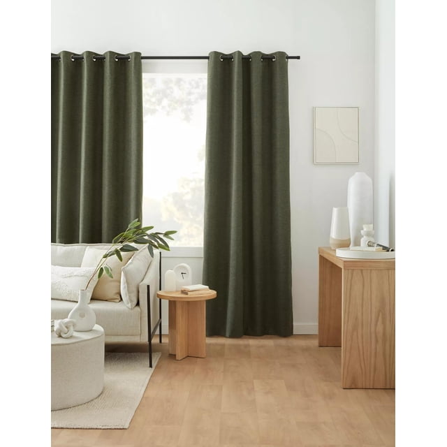 Bouclair Rideau Occultant Dion Vert Mesurant 52x96 Pouces (132x244 cm) Exposé dans un Décor de Salon Moderne. le Rideau Vert Uni Présente des Oeillets pour une Suspension Facile et Offre une filtration de la Lumière Occultante. le Rideau Est Stylé sur une Tringle à Rideaux Noire, Complétant le Mobilier Ton Neutre et la Déco en Bois dans la Pièce. un Panneau par Paquet, Vendu Séparément.