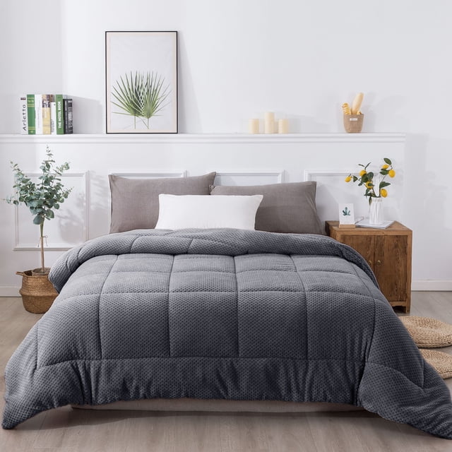 Reversible Plush Sherpa Comforter by Kasentex in grey, displayed on a neatly made bed in a modern bedroom setting. The comforter features a box-stitched design for even distribution of its down-alternative fill, ensuring warmth and comfort during cold nights. The soft brushed microfiber and faux fur texture add a cozy and luxurious feel, making it an ideal bedding set. Surrounding decor includes a wooden nightstand, potted plants, and neutral-toned pillows.