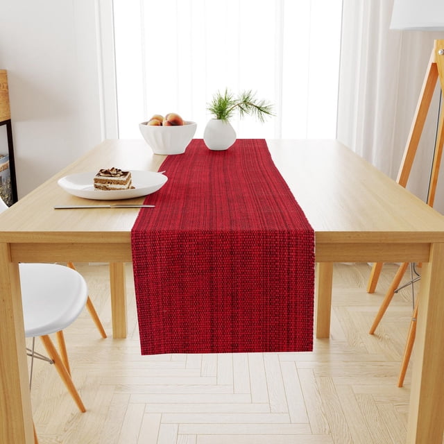 Fabstyles Casual Classic Cotton Table Runner in red woven cotton fabric measuring 13x54 inches, laid centered on a light wood dining table with a white bowl of peaches and a small white vase with pine sprigs, in a bright room with white curtains and light wood parquet flooring, ideal for dining or patio tables.