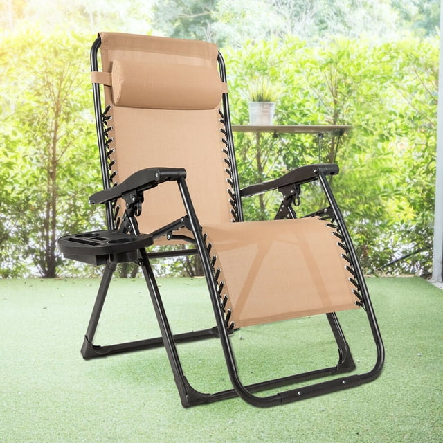 Gymax Folding Zero Weighted Lounge Chair Recliner in beige with a steel frame and fabric seat, featuring a movable pillow, adjustable backrest, and a cup holder tray. The chair is shown in an outdoor setting with greenery in the background, ideal for patio or poolside use. Lightweight and foldable for easy storage and transport.