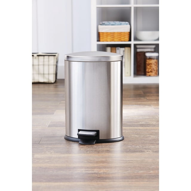Hometrends 12 Litre Stainless Steel Kitchen Garbage Can Waste Bin with Durable Foot Pedal, an oval stainless steel pedal bin with fingerprint-resistant finish, soft-close lid, and removable inner bucket, placed on wood flooring in a modern kitchen setting, suitable for bathrooms, bedrooms, or offices and ideal for hygienic hands-free waste disposal.