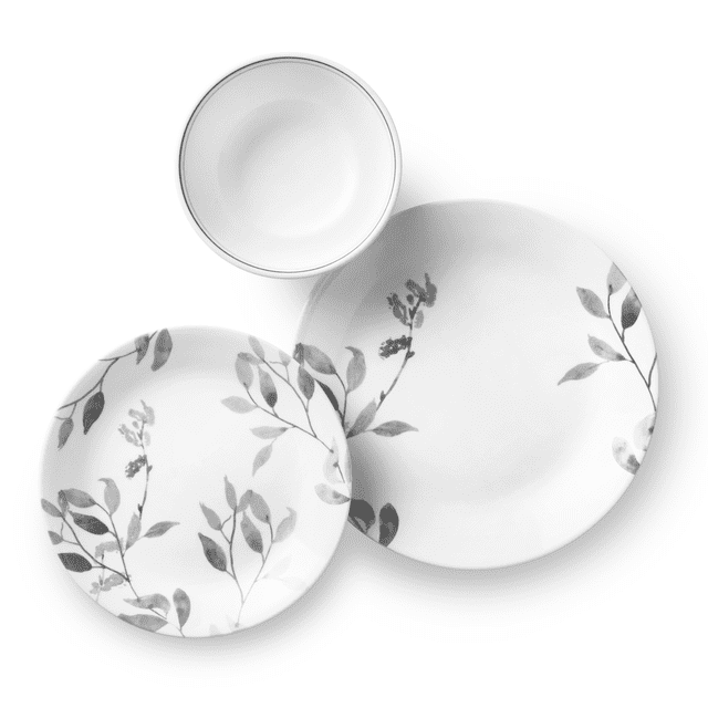 Corelle Misty Leaves 12-Piece Glass Dinnerware Set (Service for 4) showing a top-down view of a large dinner plate and smaller salad plate with gray leafy branch patterns, plus a white soup bowl with a thin gray rim. Made of durable, lightweight Vitrelle glass, this dishwasher, microwave, and oven-safe set is ideal for everyday dining and space-saving storage.
