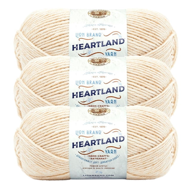 Lion Brand Yarn Heartland Yarn 3Pack featuring three skeins of light beige worsted weight acrylic yarn with branded labels. This machine washable yarn is suitable for knitting and crochet projects, offering durable and soft texture inspired by natural landscapes.