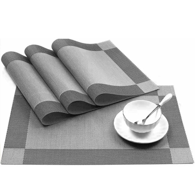 Meitianfacai Placemats Set Of 6 Washable Indoor/Outdoor Vinyl Place Mats for Dining Table. The image shows six silver PVC weave placemats with a textured design, arranged neatly with one placemat featuring a white cup and saucer with a spoon. Each placemat measures 17.71 x 11.81 inches and offers heat insulation up to 176℉ (80℃). Suitable for protecting tables from scratches and spills, these placemats are ideal for both indoor and outdoor dining settings.