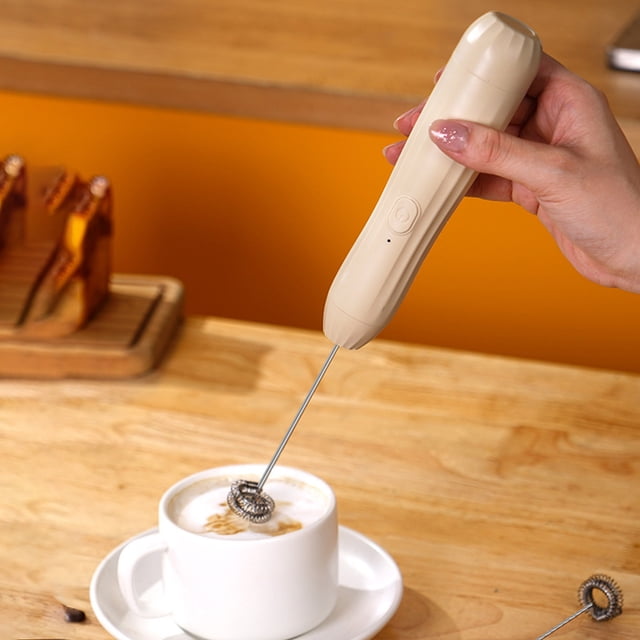 Dvkptbk Milk Frother for Coffee, a handheld foam maker in khaki color with a stainless steel whisk, shown frothing milk in a white cup on a wooden table. Ideal for cappuccino, matcha, hot chocolate, and can also be used as an eggbeater. Compact design with USB rechargeable functionality.
