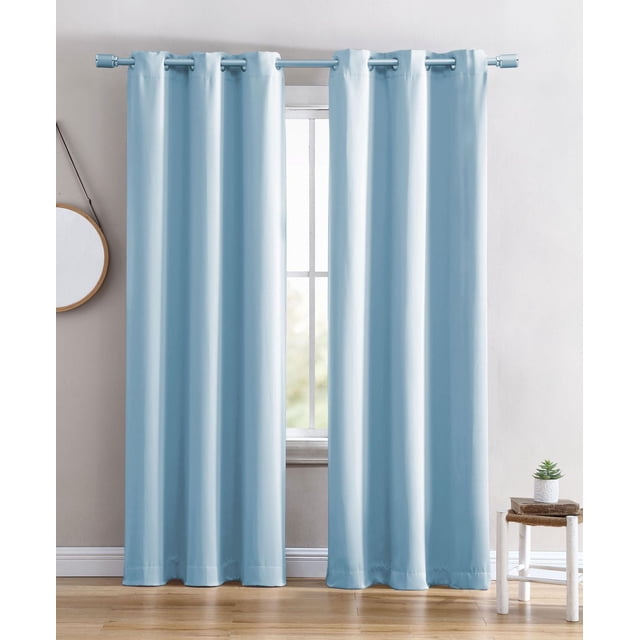 Solid Blackout Grommet Window Panel in light blue, shown as two noise-reducing panels with silver grommets hanging from a matching blue rod, blocking light from a window in a minimalist room with wood flooring, a small white stool with a plant, and a round wall mirror. The panels are machine washable and made of 100% polyester, suitable for enhancing privacy and light control.