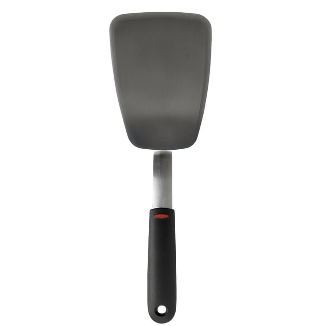 OXO SoftWorks Large Silicone Flexible Turner with a wide gray silicone head bonded to flexible stainless steel and a black soft, non-slip handle featuring a red OXO logo, designed for flipping delicate foods on non-stick cookware and suitable for turning fish or crepes.