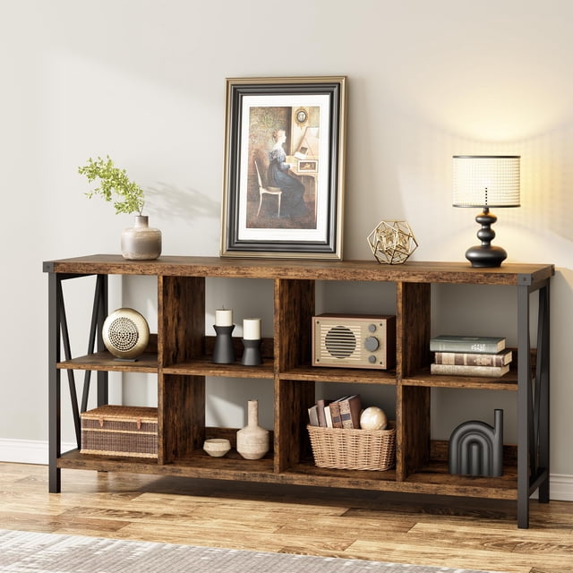 TROPOW 8 Cube Storage Organizer Bookcase, a 3-tier industrial metal horizontal bookcase with a retro brown finish. Features 8 cube compartments, a V-shaped design, and a semi-enclosed back panel for stability. Made of engineered wood and metal, measuring 62 inches long, 13.4 inches wide, and 30.1 inches high. Suitable for use as a bookshelf, TV stand, or console table in living rooms or entryways. Shown in a styled living room setting with decorative items and books.