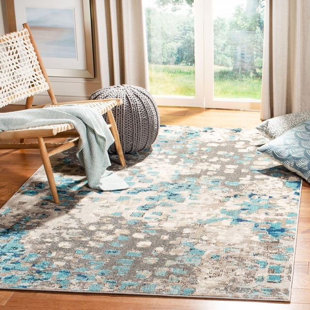 SAFAVIEH Madison Candelario Abstract Polka Dots Area Rug featuring a modern abstract polka dot pattern in blue, gray, and beige tones, power loomed for durability and easy care. The rug is placed on hardwood flooring in a bright room with a woven wooden chair draped with a light blue knitted throw, a gray knitted pouf, and blue-gray pillows near large windows with beige curtains. This accent rug is also suitable for enhancing reading nooks or lounge spaces.
