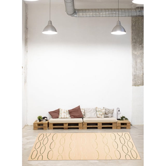 ECARPETGALLERY Elegance Beige Rug 5'1" x 7'6" features a beige indoor area rug with vertical oval patterns in green and cream, set on a concrete floor in a minimalist industrial room with white walls, placed in front of a wooden pallet sofa with beige cushions and mixed brown and patterned pillows under two metal pendant lights, ideal for accenting modern living spaces.