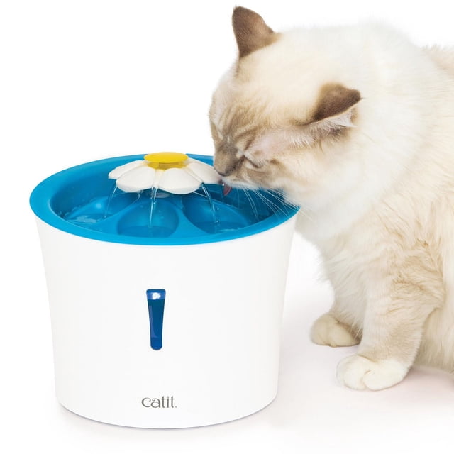 Catit Cat Flower Fountain with LED, 3 L water reservoir in white and blue plastic with a yellow-centered flower top pouring water into six pockets, featuring a water level indicator window with LED nightlight, shown with a cream cat drinking, designed to provide filtered running water with three flow settings.