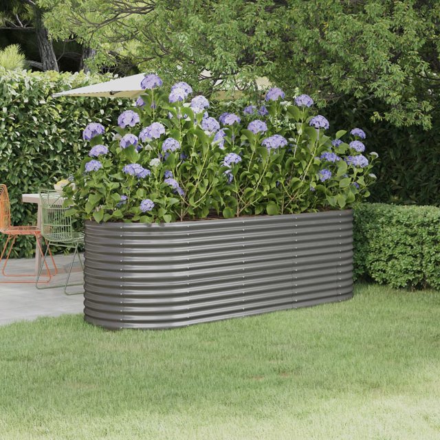 vidaXL Garden Raised Bed Powder-coated Steel 224x80x68 cm Grey. This oval-shaped raised garden bed is made of durable, powder-coated steel in a grey finish, offering resistance to rust and corrosion. It features a sturdy frame with interior support brackets and provides ample space for planting flowers, vegetables, herbs, or other plants. The raised bed is shown in an outdoor garden setting, surrounded by greenery and filled with blooming purple flowers.