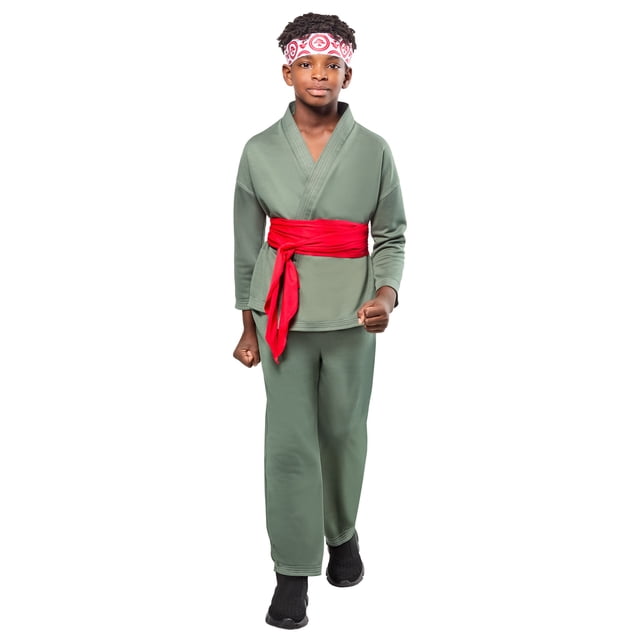 Karate Kid Legends Li Fong Costume for Kids by Rubies with a boy wearing a green polyester karate jacket and pants set, a wide red tie belt around the waist, and a printed bonsai tree headband, styled in boys size small, shown front-facing on a white background with black slip-on shoes, suitable for Halloween and themed dress-up events.