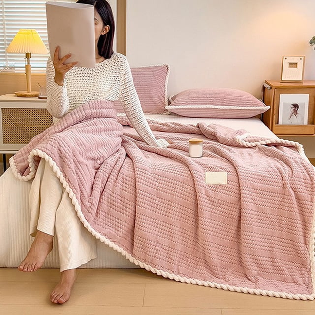 Tyidzon Throw Blanket Extra Thick Flannel Fleece Blanket with Double Layer in pink, made of microfiber polyester, measuring 200x150cm, displayed on a bed with matching pink bedding. The blanket features a textured design with a cozy and lightweight appearance, suitable for naps, couches, or beds. A person is seated on the bed, holding a book, showcasing the blanket's comfort and versatility.