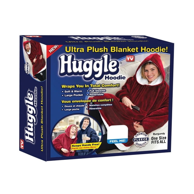 Huggle Hoodie ultra plush adult blanket hoodie in burgundy, oversized fleece with full sleeves and large front pocket, lined with white sherpa fleece, one size fits all, reversible design, shown worn while holding a remote control, ideal for warmth and comfort at home or outdoors.
