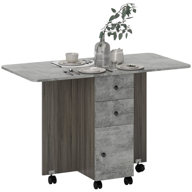 HOMCOM Foldable Dining Table in weathered grey oak finish, designed as a space-saving dining table with a drop-leaf feature that expands to seat up to six people. Includes three drawers, a cabinet for discreet storage, and six wheels for easy mobility, with four brakes for stability.