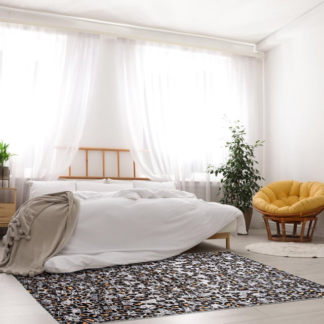 ECARPET Tapis Doux et Duveteux à Imprimé Animal pour Chambre, Cheetah Collection, Placé dans une Chambre Lumineuse avec un Cadre de Lit en Bois et une Literie Blanche. le Tapis d'Intérieur Présente un Imprimé Guépard Marbré en Tons Noir, Gris et Brun sur un Plancher de Bois Clair, Près d'Une Chaise Rembourrée Jaune et d'Une Plante Verte, Idéal pour Ajouter de la texture et du style aux Espaces Modernes.