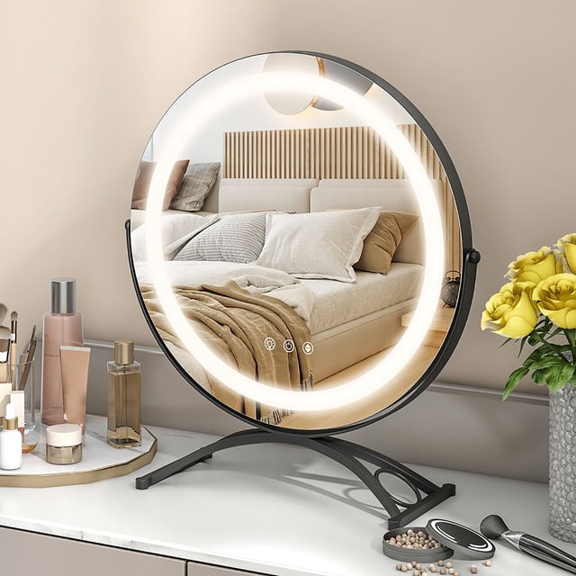 Gymax Miroir de Maquillage Rond de 16 Pieds' avec Lumières DEL à 3 Couleurs Réglables, Fonction Mémoire et Fini Noir. Ce Miroir de Maquillage Éclairé Présente un Verre Argenté Haute Définition de 16 Pouces Entouré d'Un Éclairage DEL Réglable pour une application de Maquillage Polyvalente. la base Métallique Courbée avec Patins Antidérapants Assure la Stabilité et Protège le Dessus de table. Commandes Tactiles Intelligentes sur le Miroir Permettent de Commuter Facilement entre les modes d'Éclairage et les Niveaux de Luminosité. le Miroir Est Affiché sur une Coiffeuse avec des Articles de Maquillage et un vase de Fleurs Jaunes,